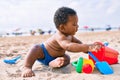 Adorable african american toddler playing with toys sitting on the sand at the beach Royalty Free Stock Photo