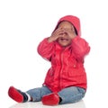 Adorable african baby sitting on the floor with red raincoat covering the face Royalty Free Stock Photo