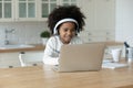 African ethnicity small girl wearing headphones, looking at computer screen. Royalty Free Stock Photo