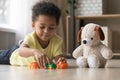 Adorable african kid lying on warm floor play with toys Royalty Free Stock Photo