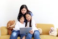 Adorable Asia happy family, cute two daughter girls with mother hold digital tablet, looking at web camera, smiling mom and Royalty Free Stock Photo