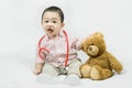 Adorable asian baby boy in pink shirt plays in doctor toy bear and red stethoscope.Health care and medical concept. Royalty Free Stock Photo