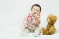 Adorable asian baby boy in pink shirt plays in doctor toy bear and red stethoscope.Health care and medical concept Royalty Free Stock Photo