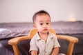 Adorable asian baby boy sitting on chair in bedroom,Happy new born kid looking to camera Royalty Free Stock Photo