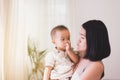 Adorable asian baby boy sucking thumb with mom carrying in bedroom,Happy new born kid Royalty Free Stock Photo