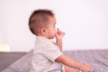 Adorable asian baby boy sucking thumb while sitting in bedroom,Happy new born kid Royalty Free Stock Photo