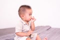 Adorable asian baby boy sucking thumb while sitting in bedroom,Happy new born kid Royalty Free Stock Photo