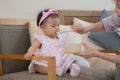 Adorable Asian baby eating food from spoon, mother feeding daughter puree or solid foods, sitting on chair at home. Little cute Royalty Free Stock Photo