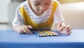 Adorable Asian boy of preschool age looking at colorfull pencils while sitting at the desk in his room at home