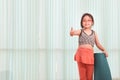 Adorable Asian girl doing yoga exercise, smiling cute child standing with yoga mat and giving thumbs up at indoor studio, sporty Royalty Free Stock Photo