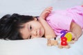 Adorable Asian girl lying down playing wooden figures toys on mattress. Child looks at the camera. Little kid relaxing day.