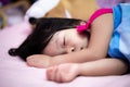 Adorable Asian girl sleeps on a soft mattress with ease. Child is covered in a blue blanket. Kid sleep during the day.