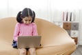 An adorable Asian girl wearing a pink shirt is happily sitting at her laptop notebook computer Royalty Free Stock Photo