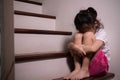 Adorable asian girl who expresses her sadness emotion on house stair alone shows concept of depression, emotional pain and Royalty Free Stock Photo