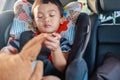 Adorable Asian kid boy Toddler age 1-year-old Protection Sitting in the Car Seat with Safety Belt Locked and Holding Bear Doll Royalty Free Stock Photo
