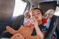 Adorable Asian kid boy Toddler age 1-year-old Protection Sitting in the Car Seat with Safety Belt Locked and Holding Bear Doll Royalty Free Stock Photo