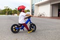 Adorable Asian kid boy Toddler age 1-year-old, Wearing a Safety Helmet and Learning to Ride a Balance Bike in the Play Space