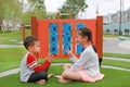 Adorable Asian little boy and young girl kid sitting in the garden playground with playing rock scissors paper game