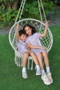 Adorable Asian little boy and young girl kid sitting together on the white cradle or swing in the garden Royalty Free Stock Photo