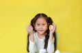 Adorable asian little child girl playing plastic eggs developmental puzzle isolated on yellow background