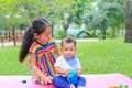 Adorable Asian sister sitting on pink mattress mat take care her little brother to drinking water from Baby sippy cup with straw Royalty Free Stock Photo