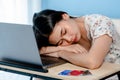 Adorable Asian woman falling asleep on the arm on table in front of a laptop computer after a tiring day Royalty Free Stock Photo