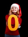Beautiful Santa girl holding a yellow zero number on a black background. Christmas 2018 concept. Royalty Free Stock Photo