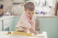 Adorable baby in an apron makes cookies from dough in the kitchen Royalty Free Stock Photo