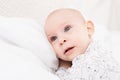 Adorable baby boy with blue eyes lying on a bed, looking away from camera. Cute toddler in pyjamas Royalty Free Stock Photo