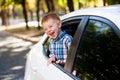 Adorable baby boy in the car. Laughing boy looks out of the car window. Royalty Free Stock Photo