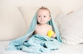 Portrait of adorable baby boy covered in blue towel sitting on bed with yellow rubber duck Royalty Free Stock Photo