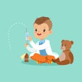 Adorable baby boy dressed as a doctor playing with teddy bear toy. Kid preparing syringe for his sick patient Royalty Free Stock Photo