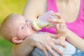 Adorable baby boy drinking milk from bottle in mother hands. Mom feeding child fo artificial nutrition formula Royalty Free Stock Photo