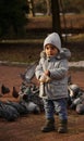 Adorable baby boy feeding pigeons at the park in winter Royalty Free Stock Photo