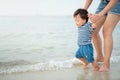 Baby boy making his first steps on the beach with his mother Royalty Free Stock Photo