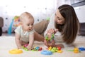 Adorable baby and young woman playing in nursery. Happy family having fun with colorful toy at home. Royalty Free Stock Photo