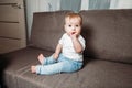 Adorable baby boy sitting on couch with fingers in his mouth Royalty Free Stock Photo