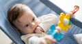 Adorable baby boy sitting in his rocker chair, playing with rotating toys. Royalty Free Stock Photo