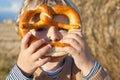 Adorable baby boy with soft pretzel in evening sun