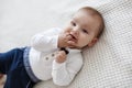 Cute baby lies and crawls on a white bed in a bright bedroom alone. Royalty Free Stock Photo