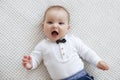 Cute baby lies and crawls on a white bed in a bright bedroom alone. Royalty Free Stock Photo