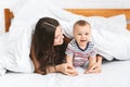 Adorable baby crawling on bed, hiding under blanket with mom Royalty Free Stock Photo