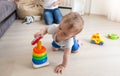 Adorable baby crawling on floor and assembling colorful toy tower Royalty Free Stock Photo