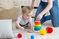 Adorable baby crawling on floor and assembling toy tower with mo Royalty Free Stock Photo