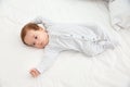 Adorable baby in cute footie on white sheet