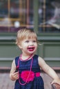 Adorable baby in a dress paints lips with lipstick