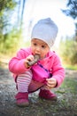 Adorable baby ducking on forest path in nature. Portrait of 1 year old girl in woods with pine cone in month Royalty Free Stock Photo