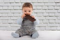 Adorable baby eating a plate of chocolate in front of a white br Royalty Free Stock Photo