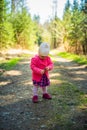 Adorable baby on forest path in nature. Portrait of 1 year old girl in woods with pine cone