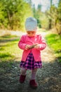 Adorable baby on forest path in nature. Portrait of 1 year old girl in woods with pine cone